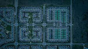 Navigating the Financial Landscape: Expert Strategies for Informed Decision-Making Aerial view of a structured suburban neighborhood at dusk, highlighting geometric patterns of streets and rooftops with green solar panels, symbolizing financial planning and order.